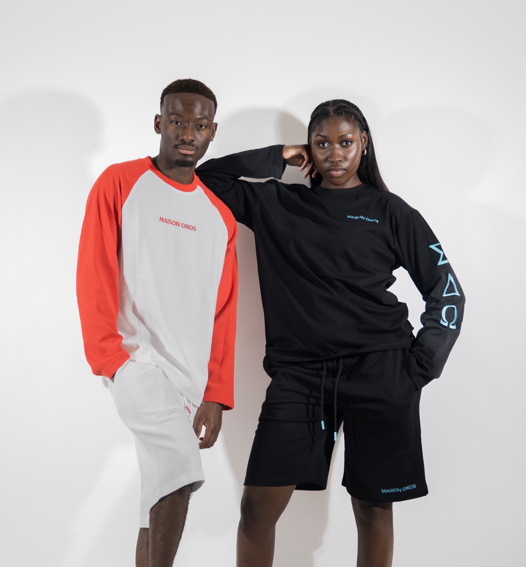 Femme appuyée sur l'épaule d'un homme, contrastant l'ensemble noir et le look raglan blanc et rouge.