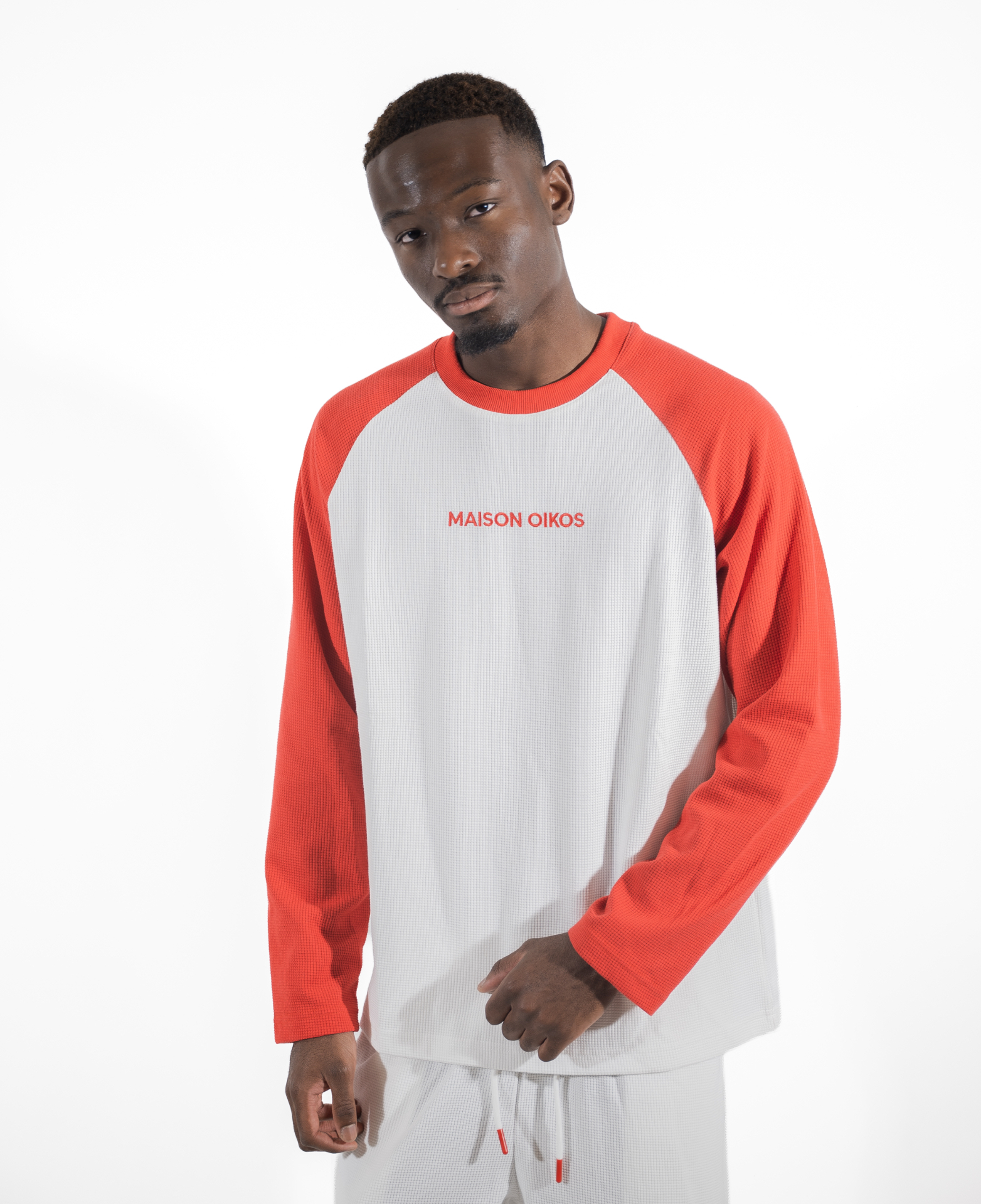 Homme portant le t-shirt raglan blanc à manches rouges avec short blanc assorti.